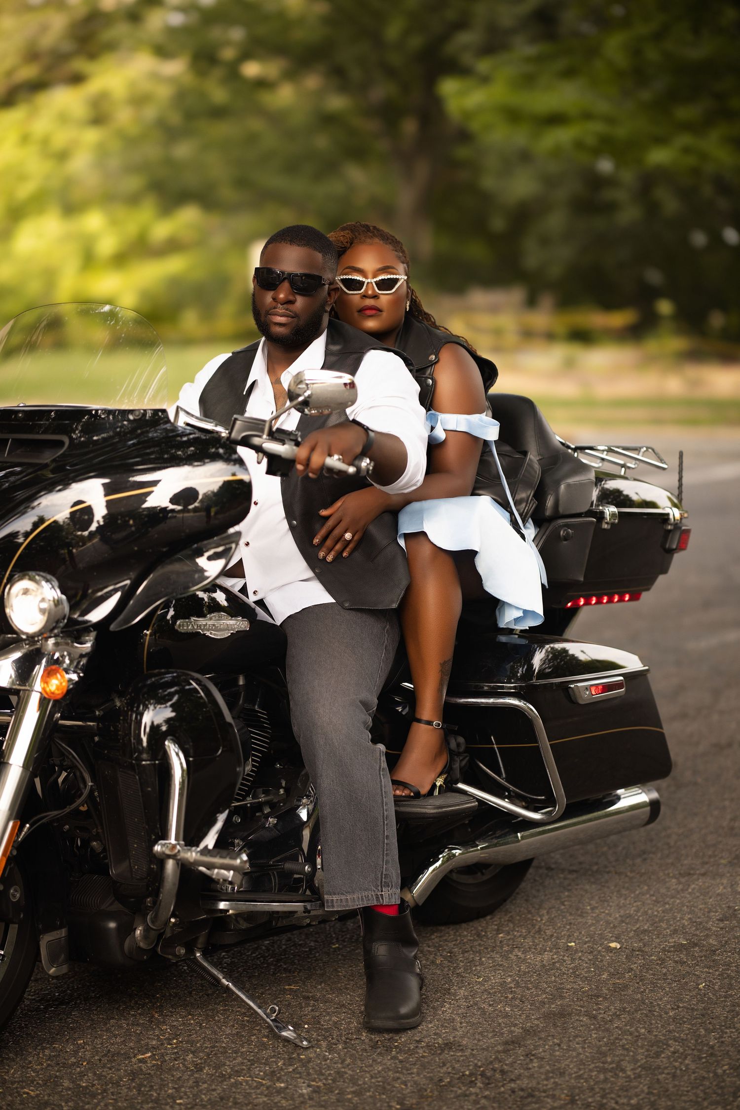 Couple poses with black and white motorcycle during outdoor photoshoot.