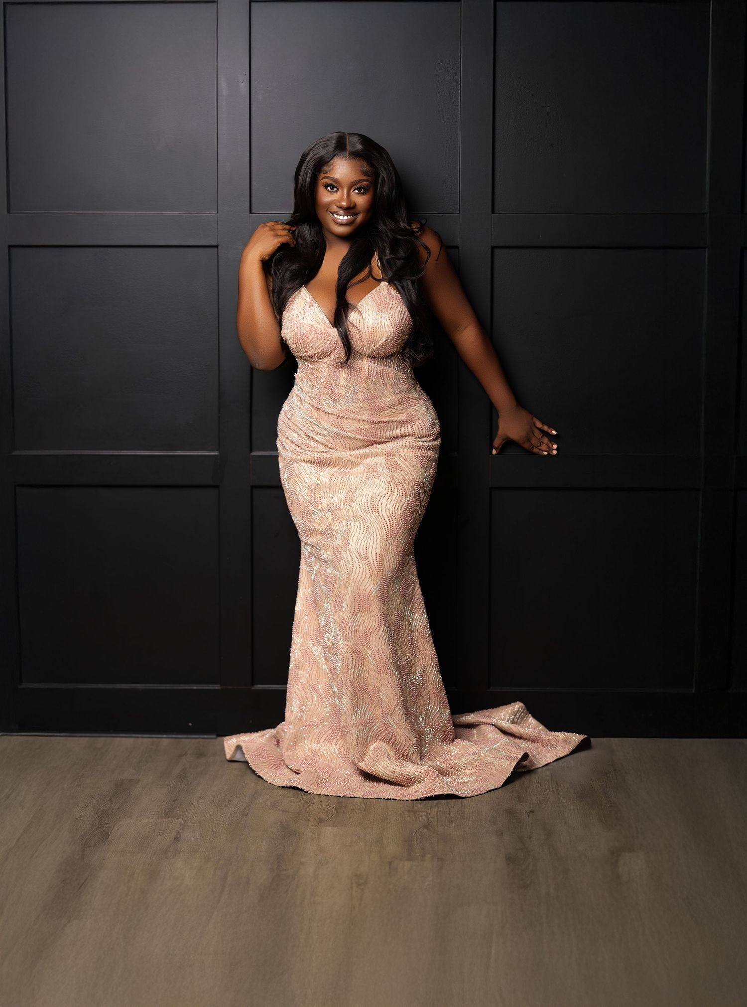 Elegant photo series in a blush pink gown against black paneled wall and wooden floor.