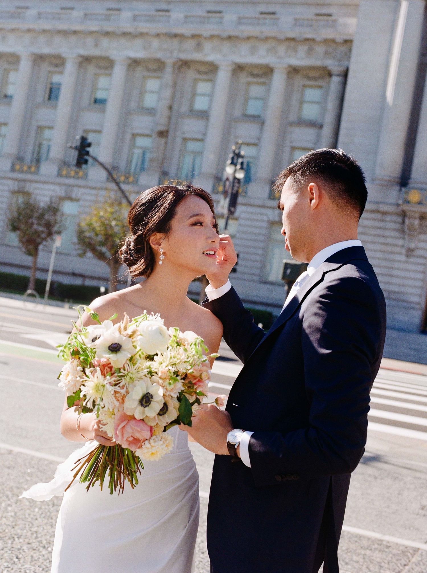 Groom brushes bride's hair outside of SF City Hall.