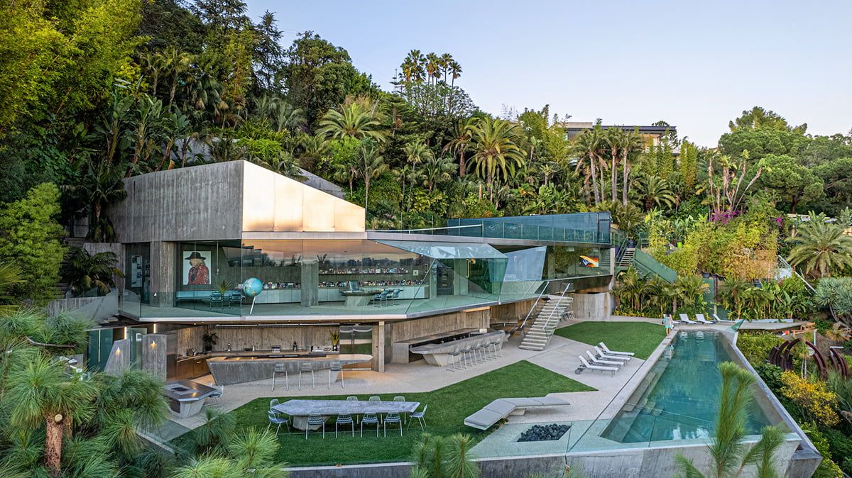 A stunning modern glass and concrete luxury home with a pool nestled among lush tropical greenery.