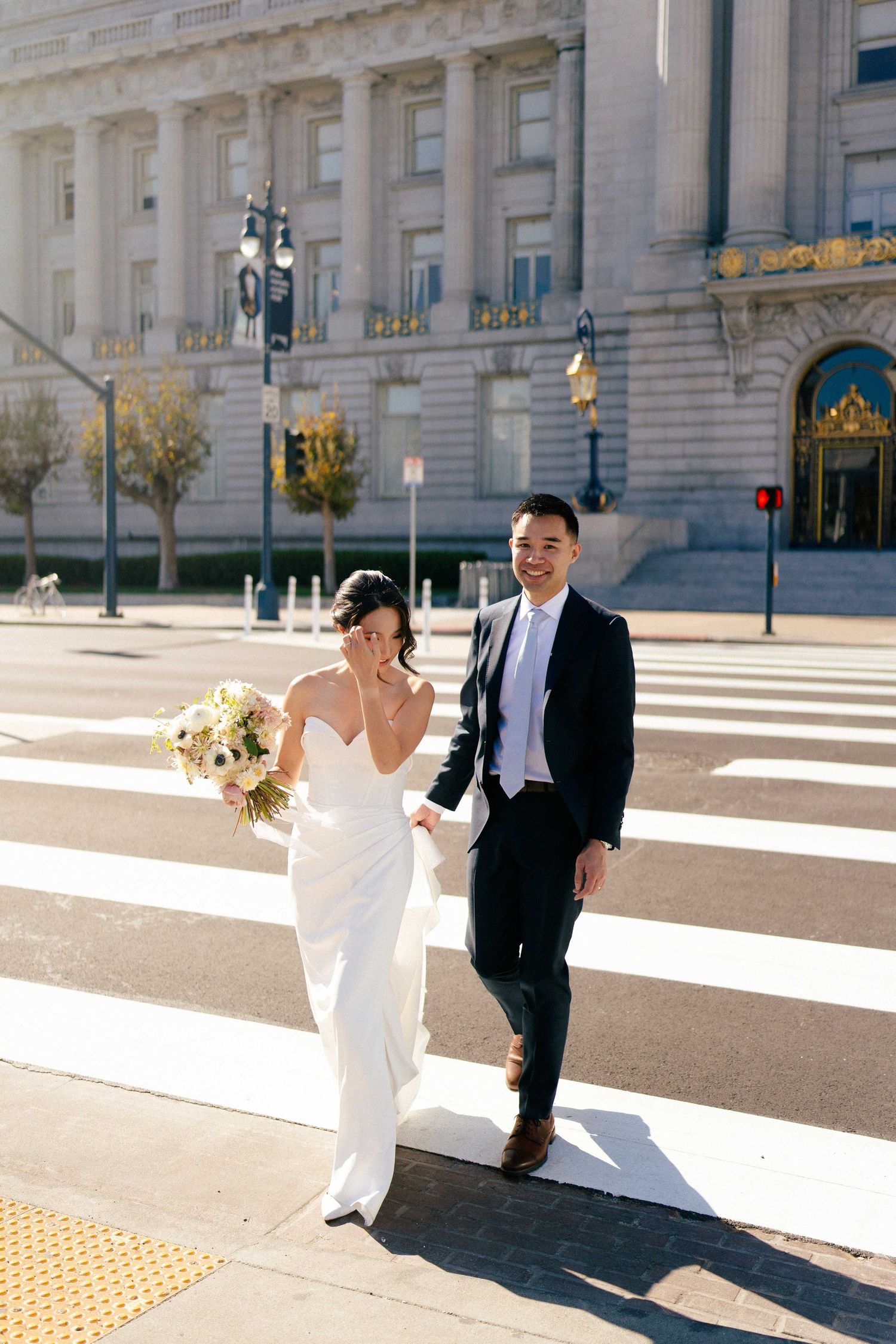 Wedding couple crossing street in front of San Francisco City Hall.