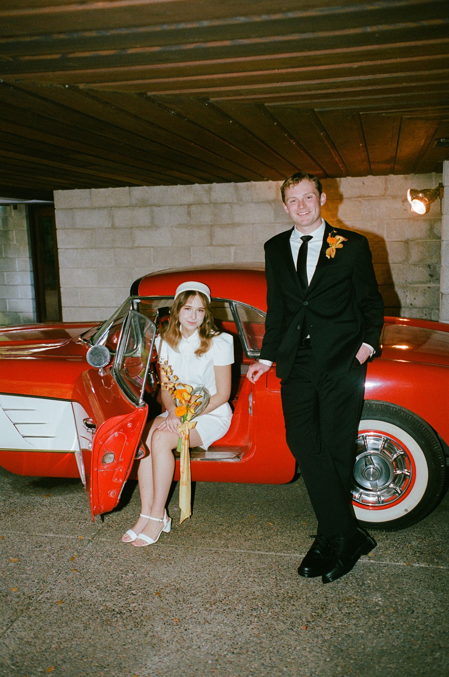 Bride and groom next to each other in vintage car.