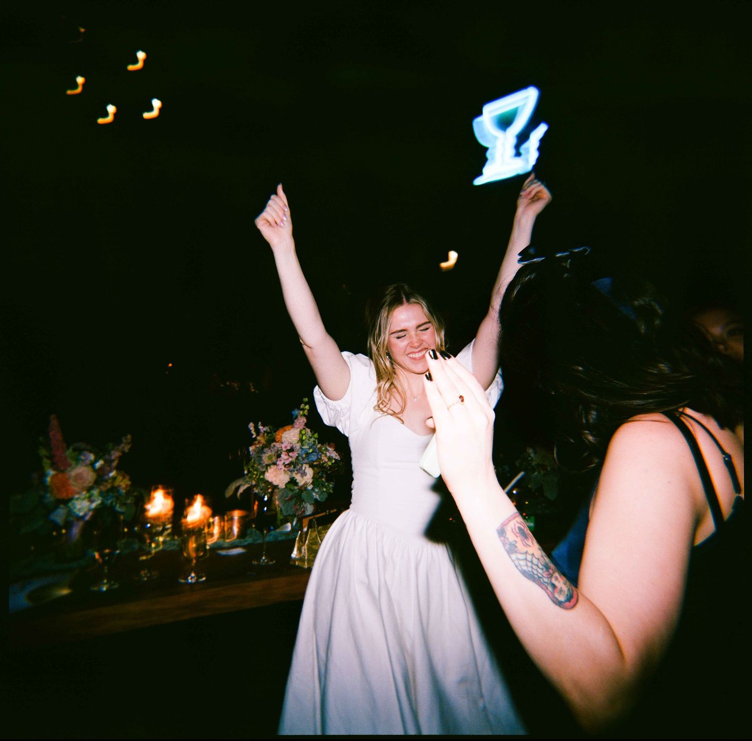 People dancing and celebrating at a dark nightclub with musical note decorations visible in the background.