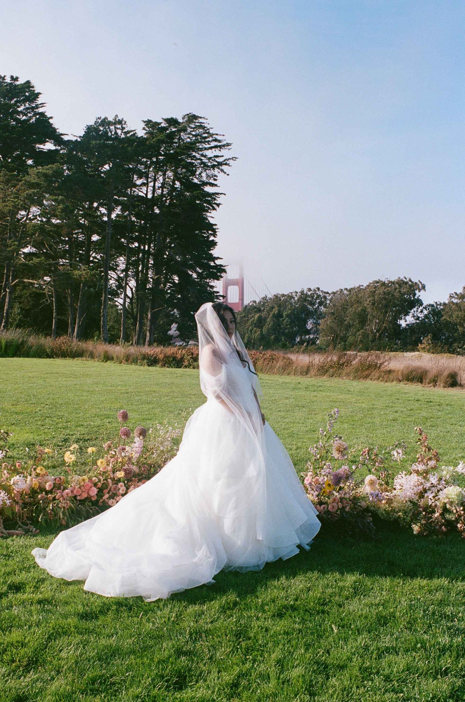 Bride standing in front of grounded floral arch.