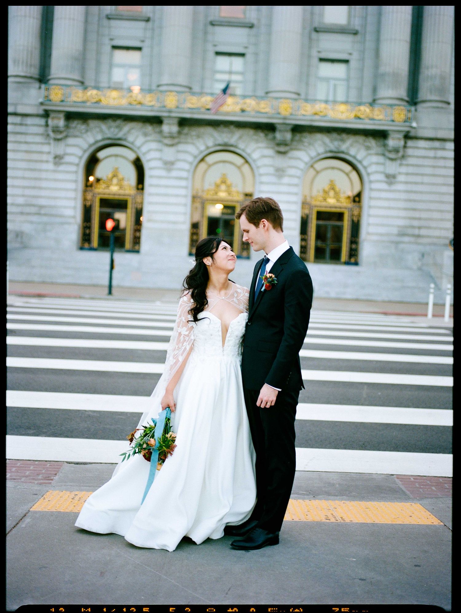 Couple in wedding attire standing outside a SF City Hall.
