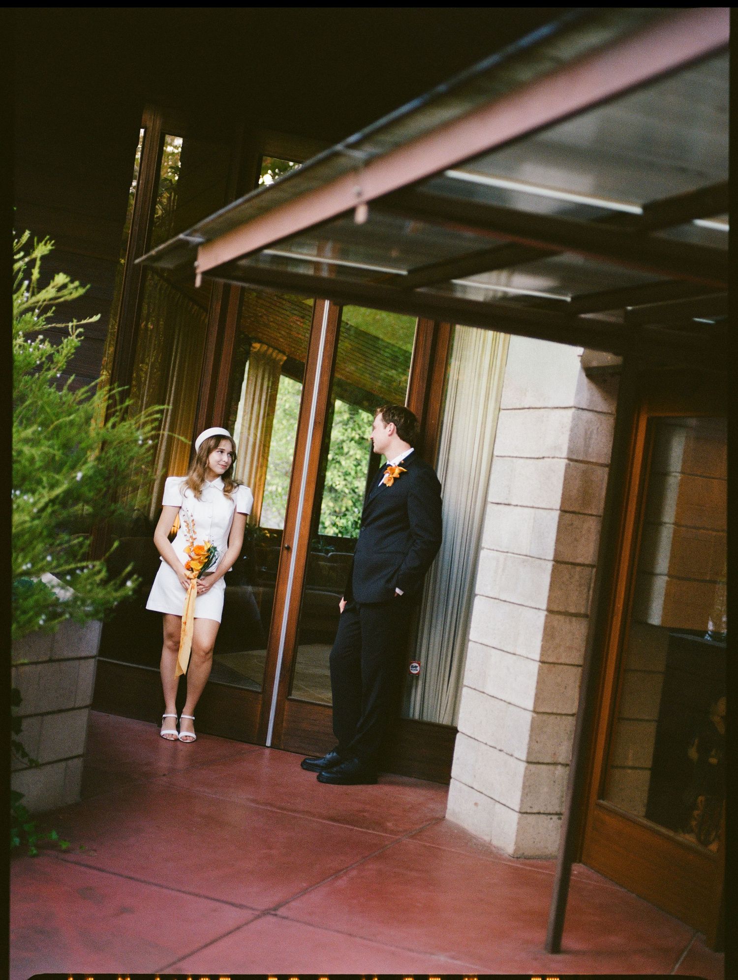 Bride and groom standing in front of Frank Lloyd Wright house.