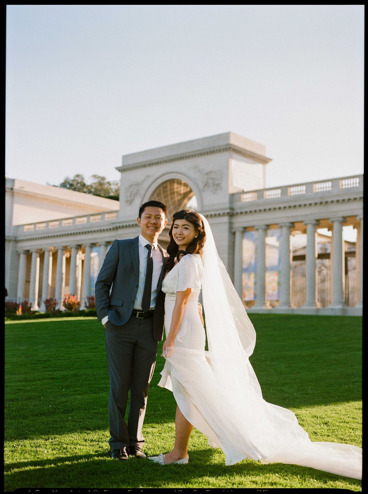 Wedding couple posing in front of classical archway and columns  at the Legion of Honor.