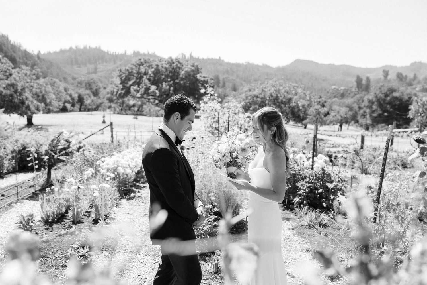 Black and white photo of bride and groom sharing a first look moment in a vineyard setting.