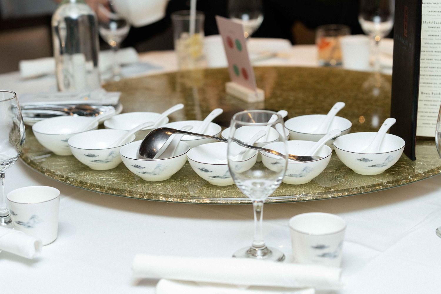 Small white serving bowls arranged on a round silver tray at a formal table setting.