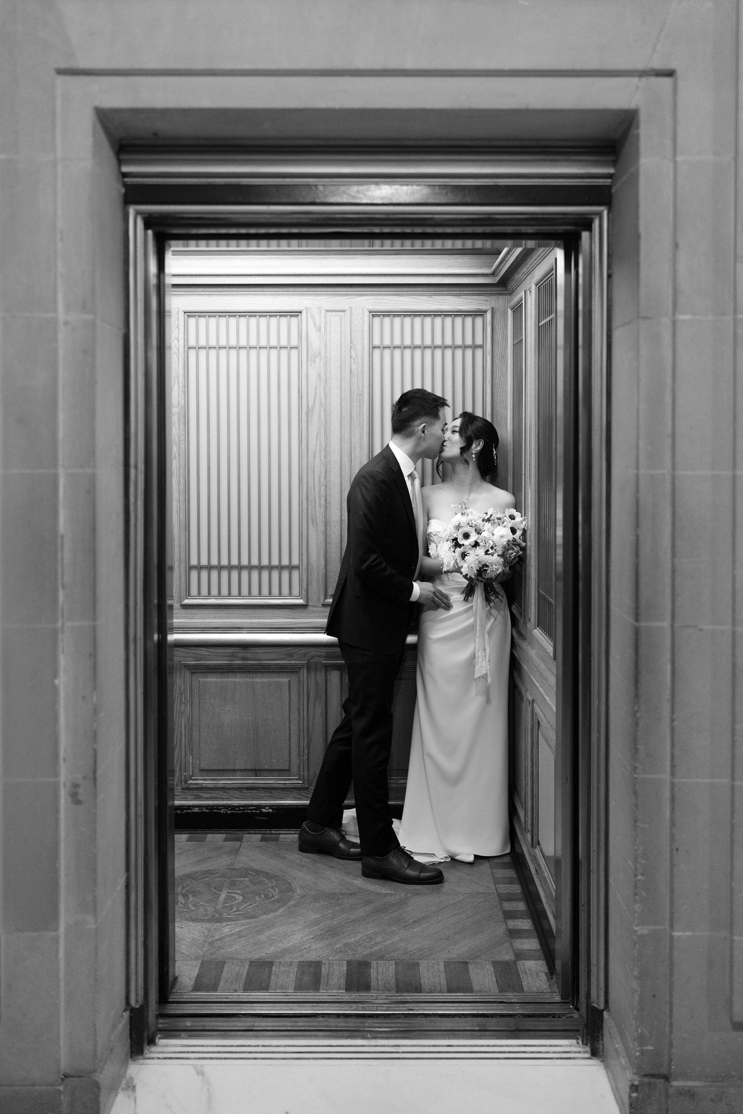 Couple kissing in the corner of the elevator.