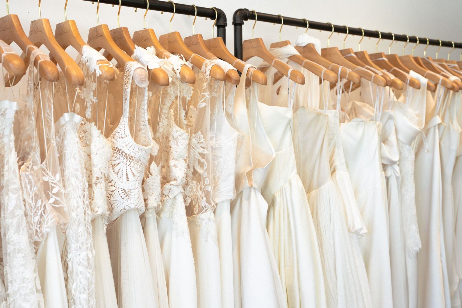 A rack of elegant white wedding dresses displayed on hangers in WildBride bridal boutique.