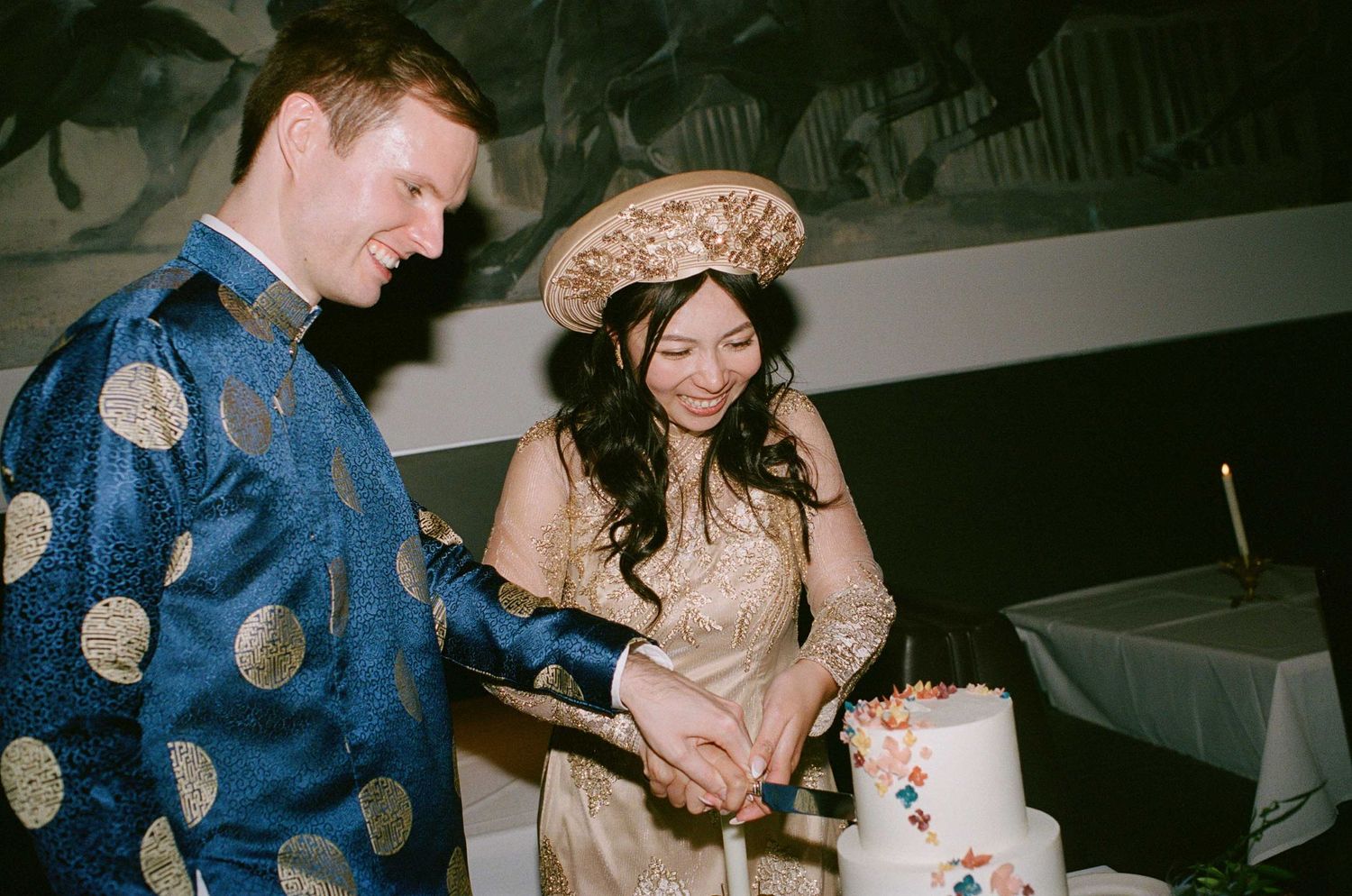 Couple cutting their wedding cake at an evening reception celebration.