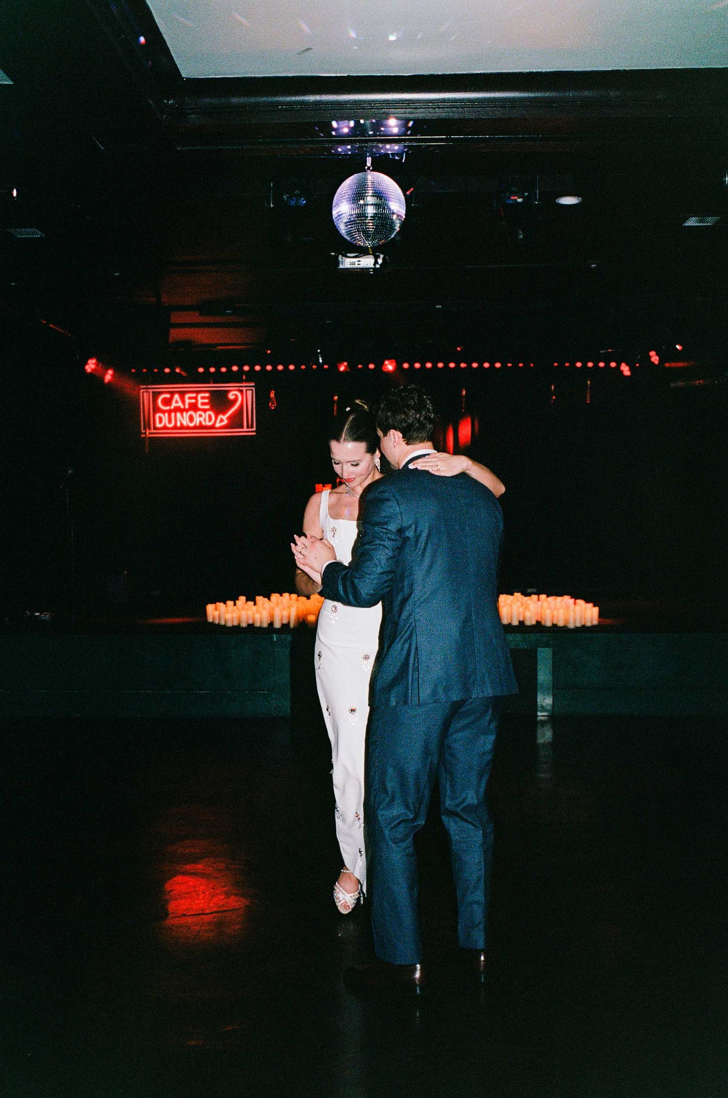 Couple sharing first dance under disco ball at Cafe du Nord wedding reception with candlelit backdrop.