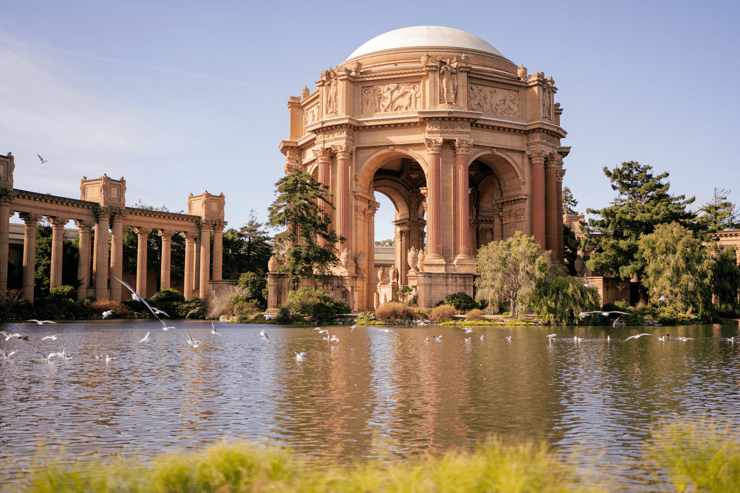 The Palace of Fine Arts dome reflects in the lagoon on a sunny day in San Francisco.