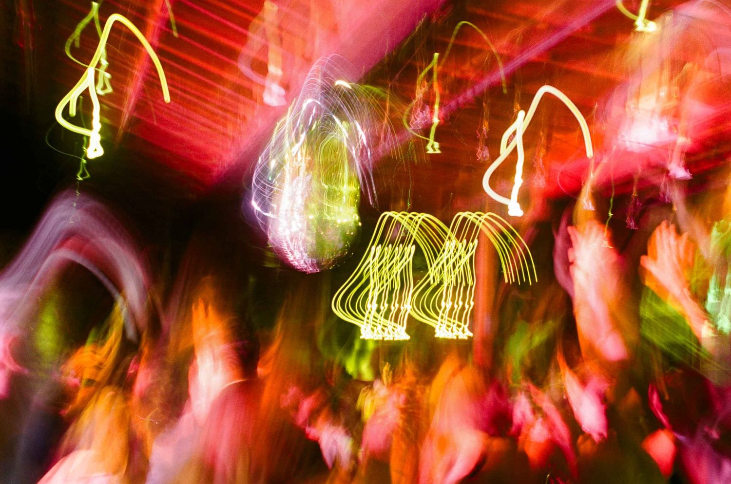 Abstract motion blur of colorful neon lights and dancing figures at a vibrant nightclub party.