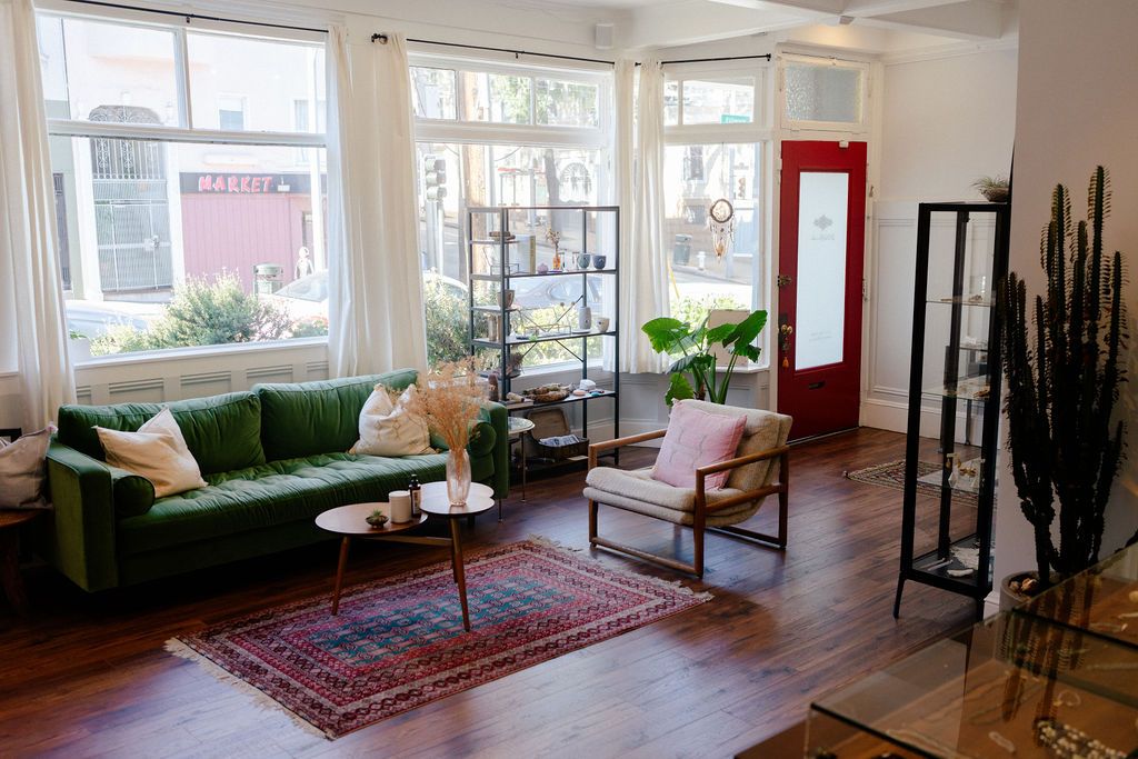 Bright contemporary living space featuring emerald sofa, area rug, and indoor plants.