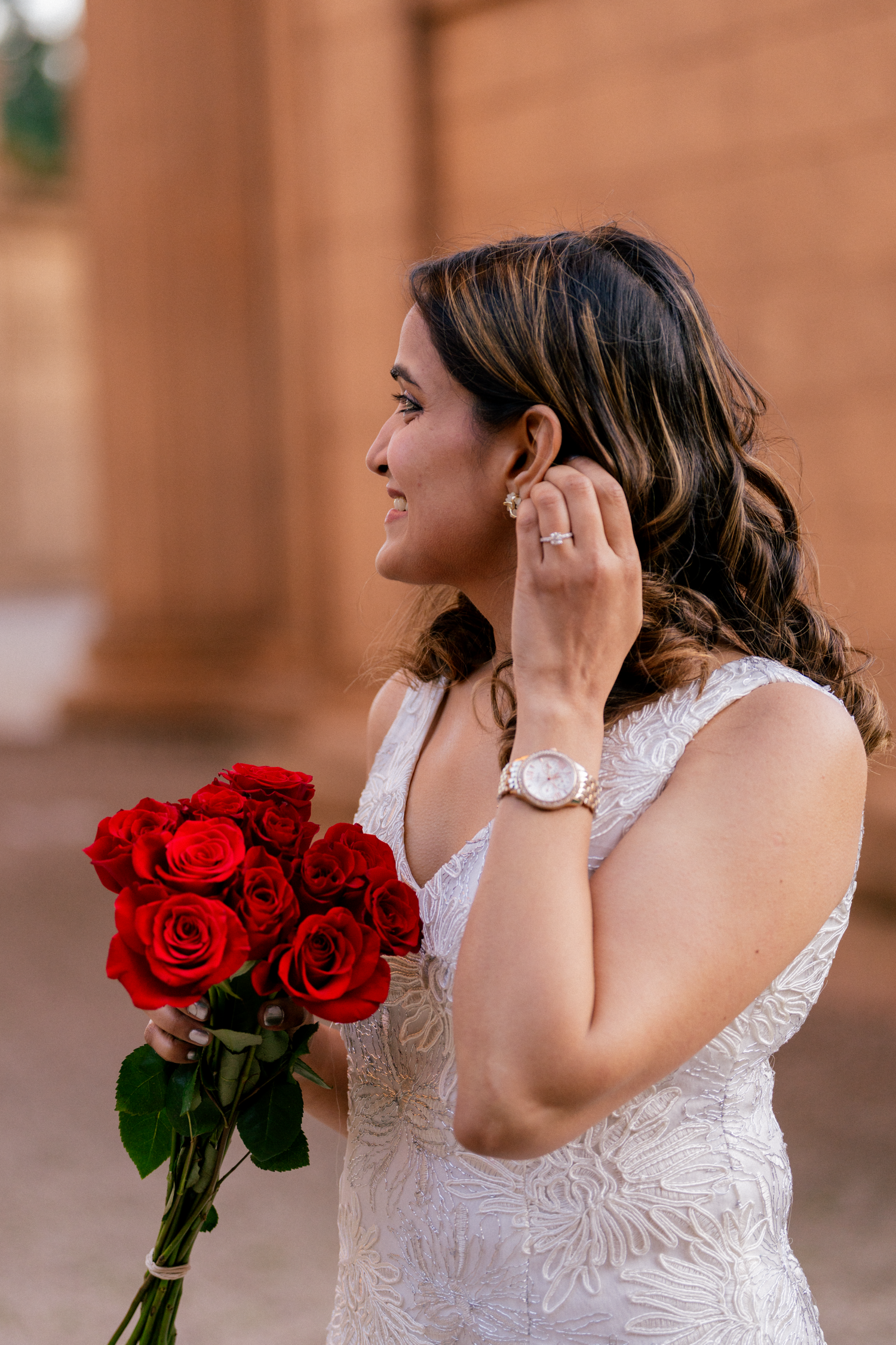 A person in white holds red roses while showing off a ring at the Palace of Fine Arts.