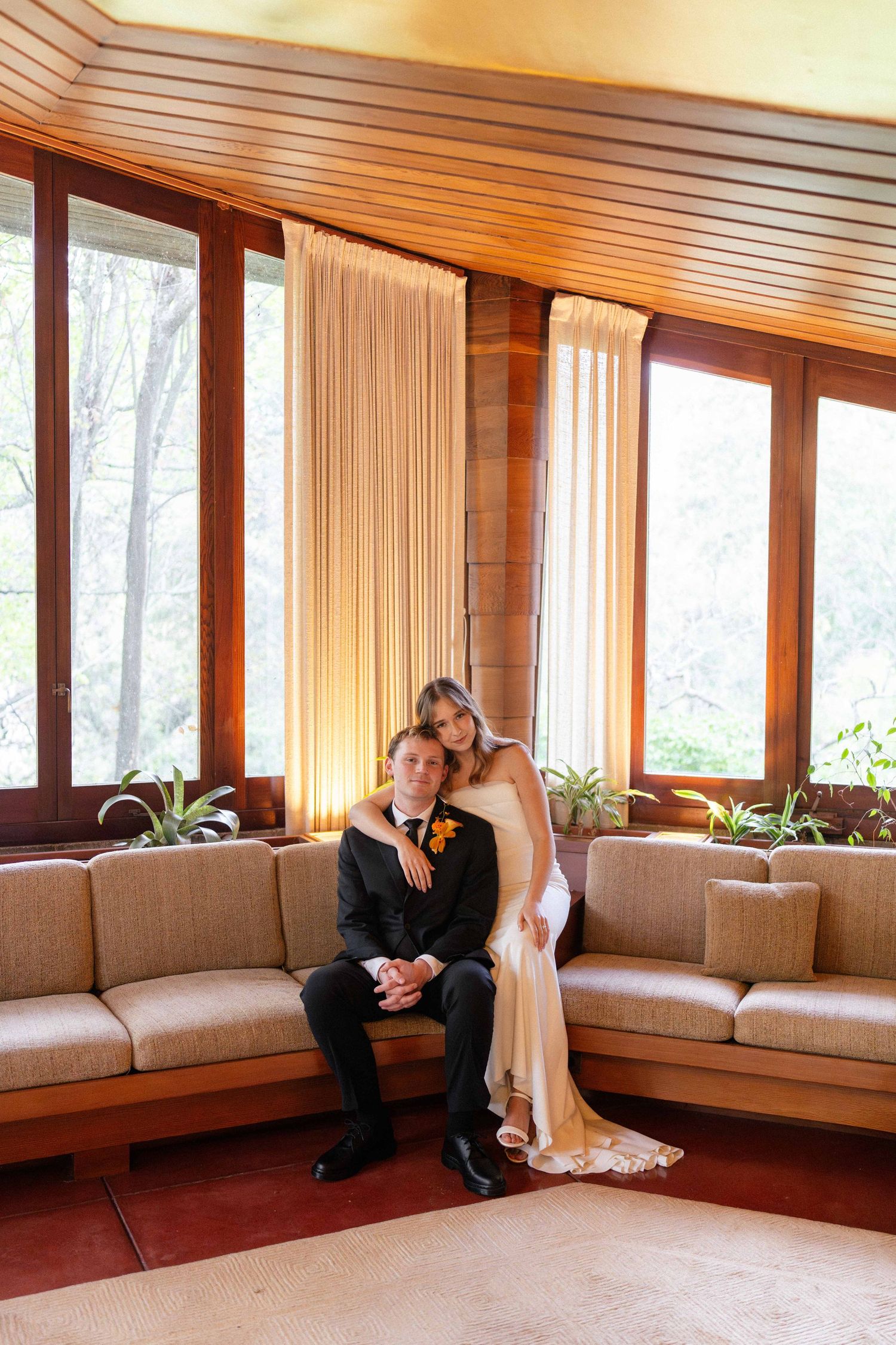 Bride with arm around groom sitting in a mid-century modern living room.