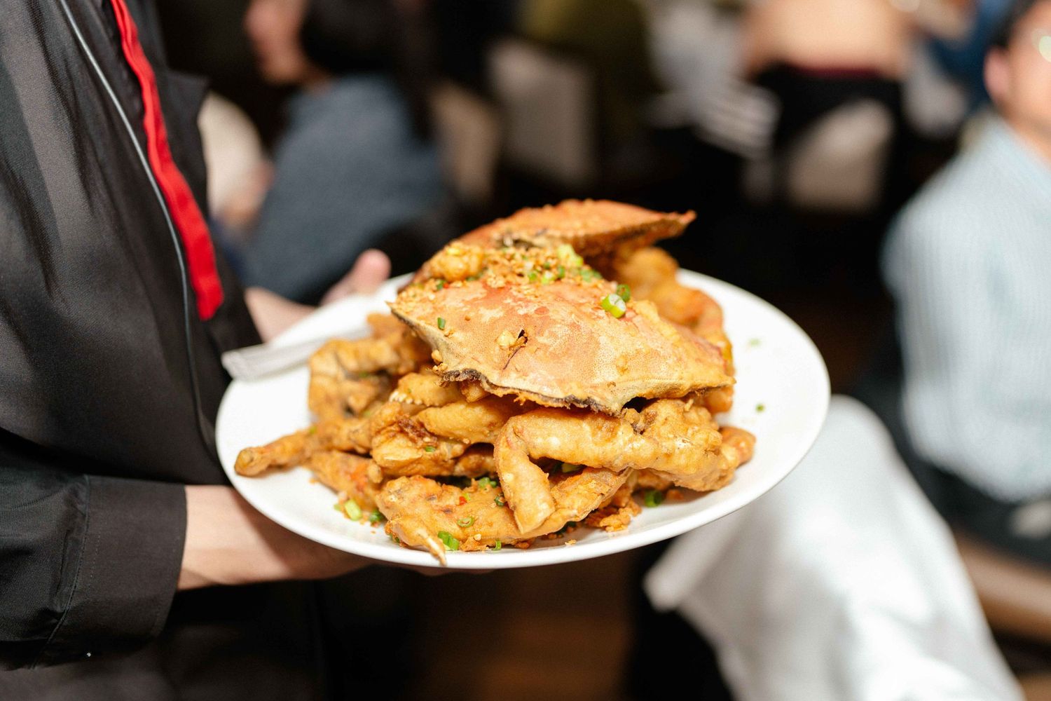 A plate of golden-brown fried appetizers being served at an event.