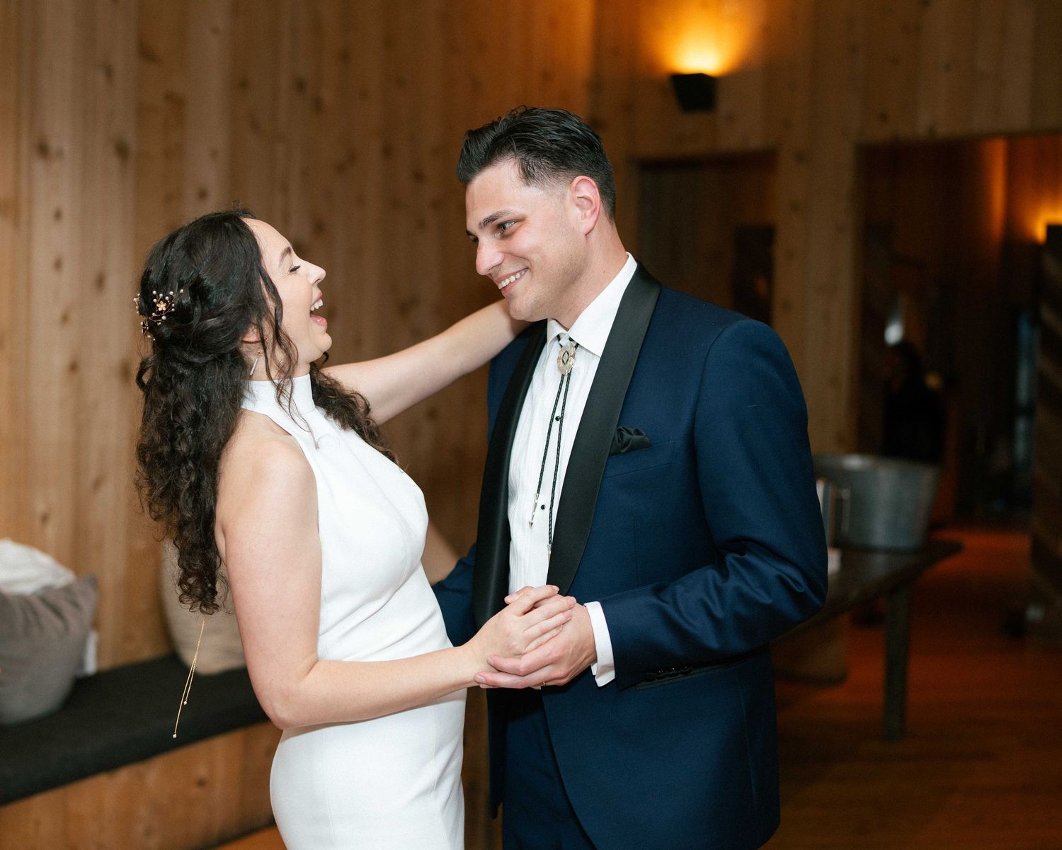 Bride and groom sharing a tender first dance moment, smiling at each other in elegant wedding attire.