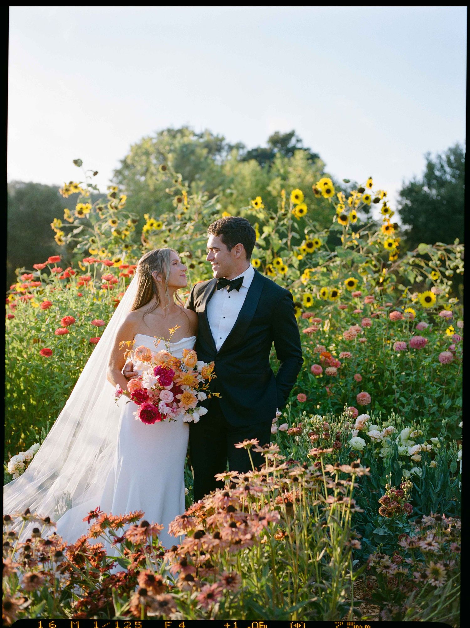 Bride and groom looking at each other in a flower field.