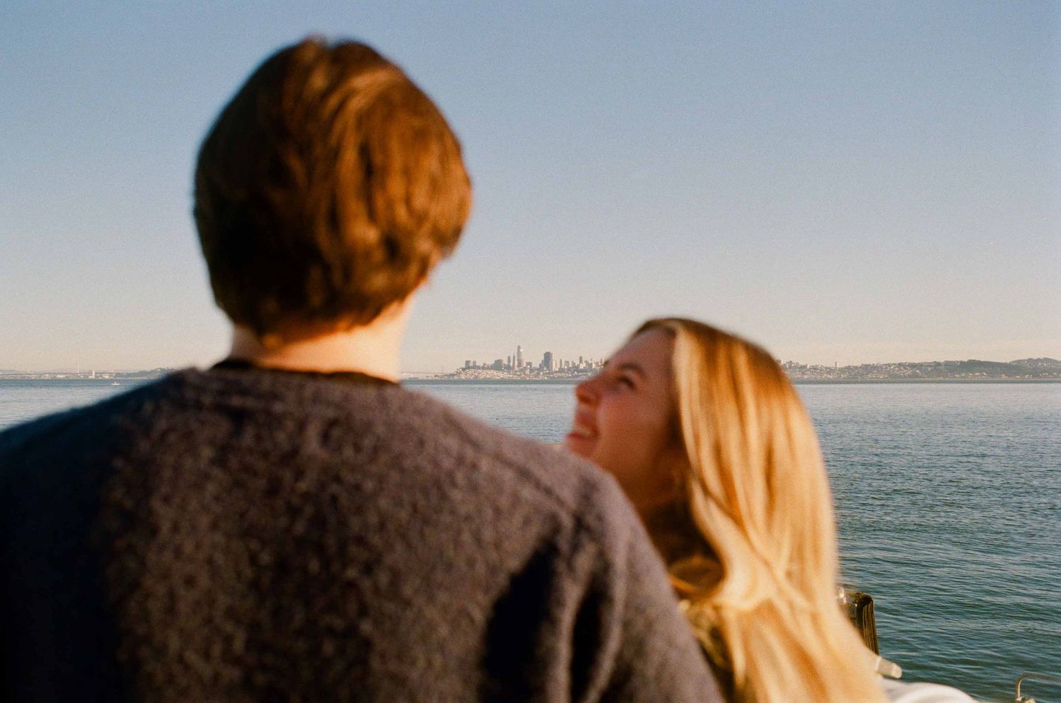 Couple enjoys romantic waterfront moment with San Francisco city skyline in background.