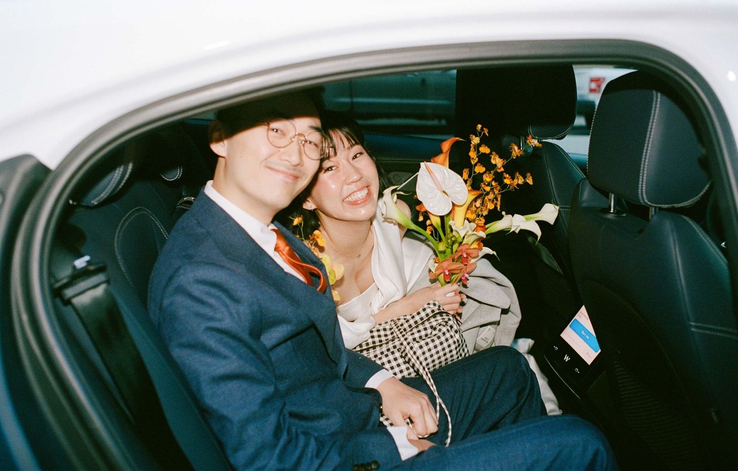 Bride and groom smiling in the back of a Waymo car.