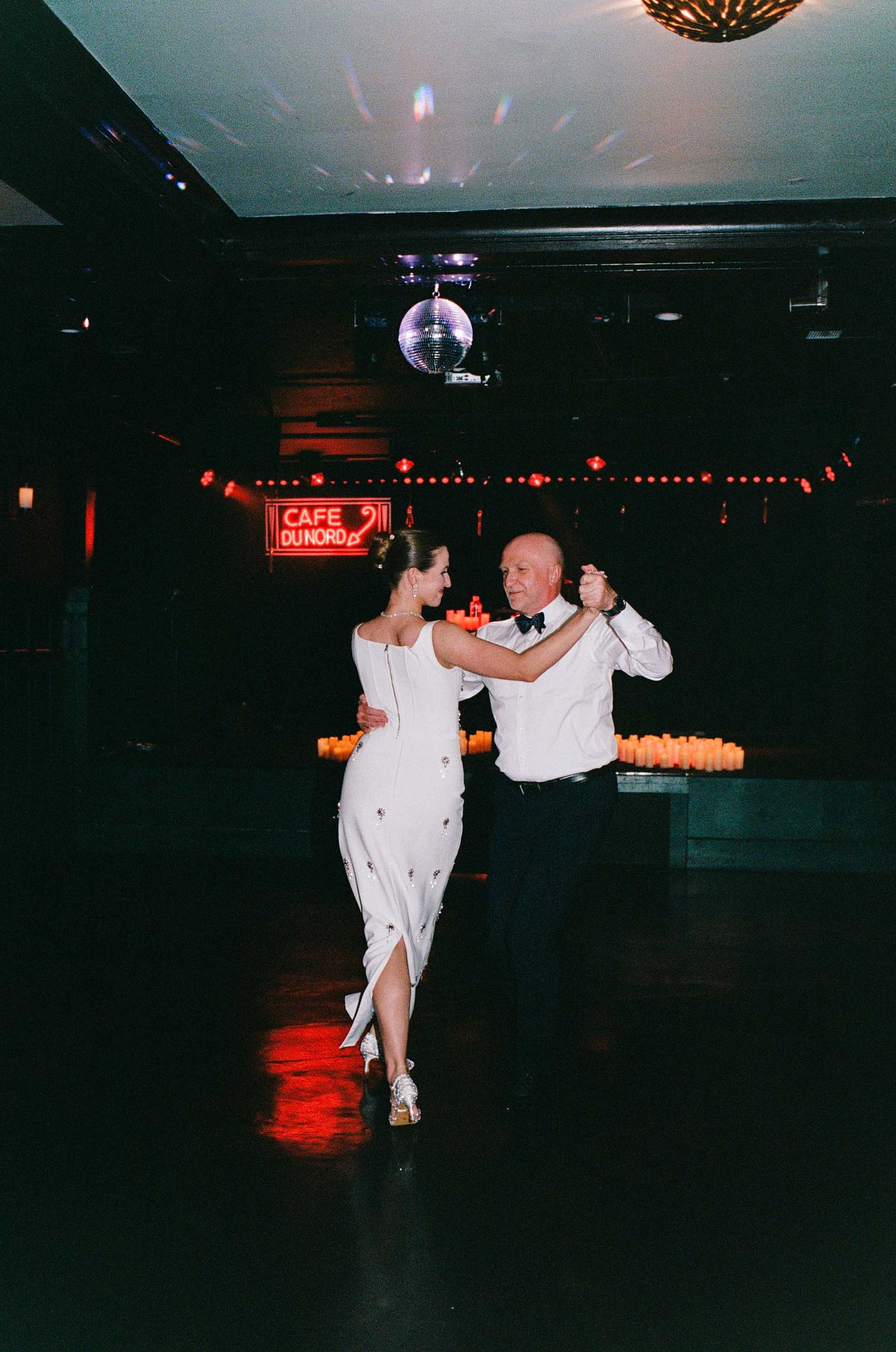 Couple sharing a romantic first dance at Cafe Dundas, illuminated by a disco ball and warm candlelight.
