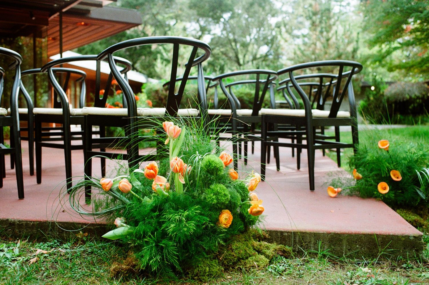 Mid-century modern chairs and grassy mounds with orange flowers.