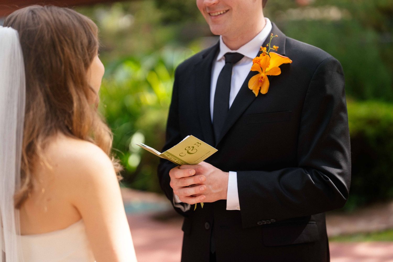 Close up of groom holding vow book.
