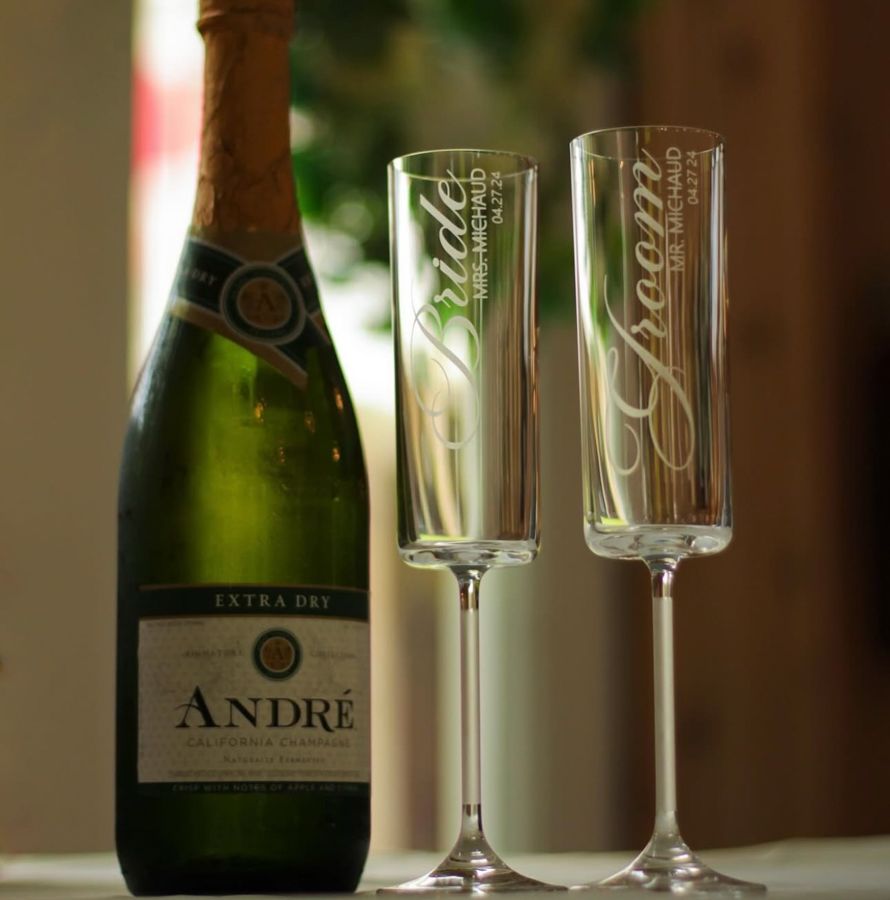 Andre Extra Dry champagne bottle beside engraved Bride and Groom crystal flute glasses for wedding toasts.