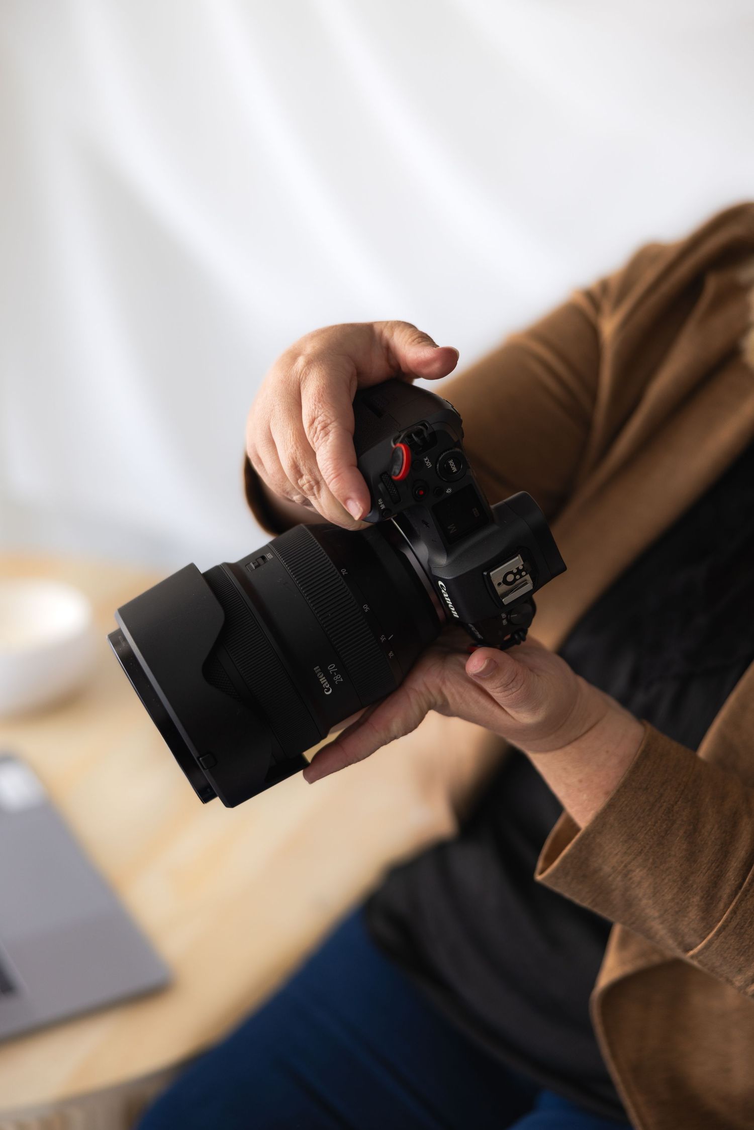 Close-up of hands holding a professional DSLR camera with wide-angle lens indoors.