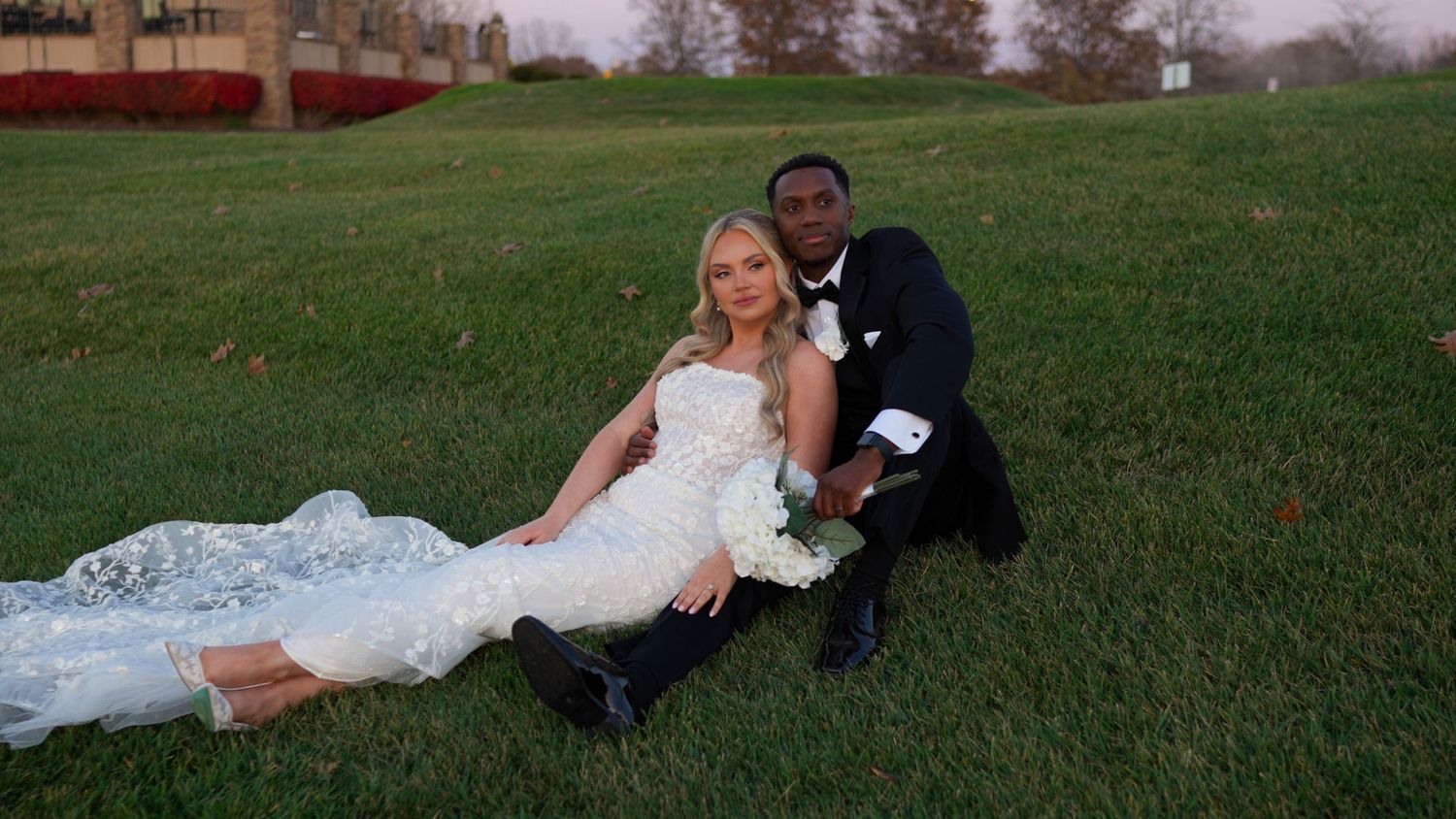 Newlyweds share intimate moments during their outdoor photo session on a grassy hill.