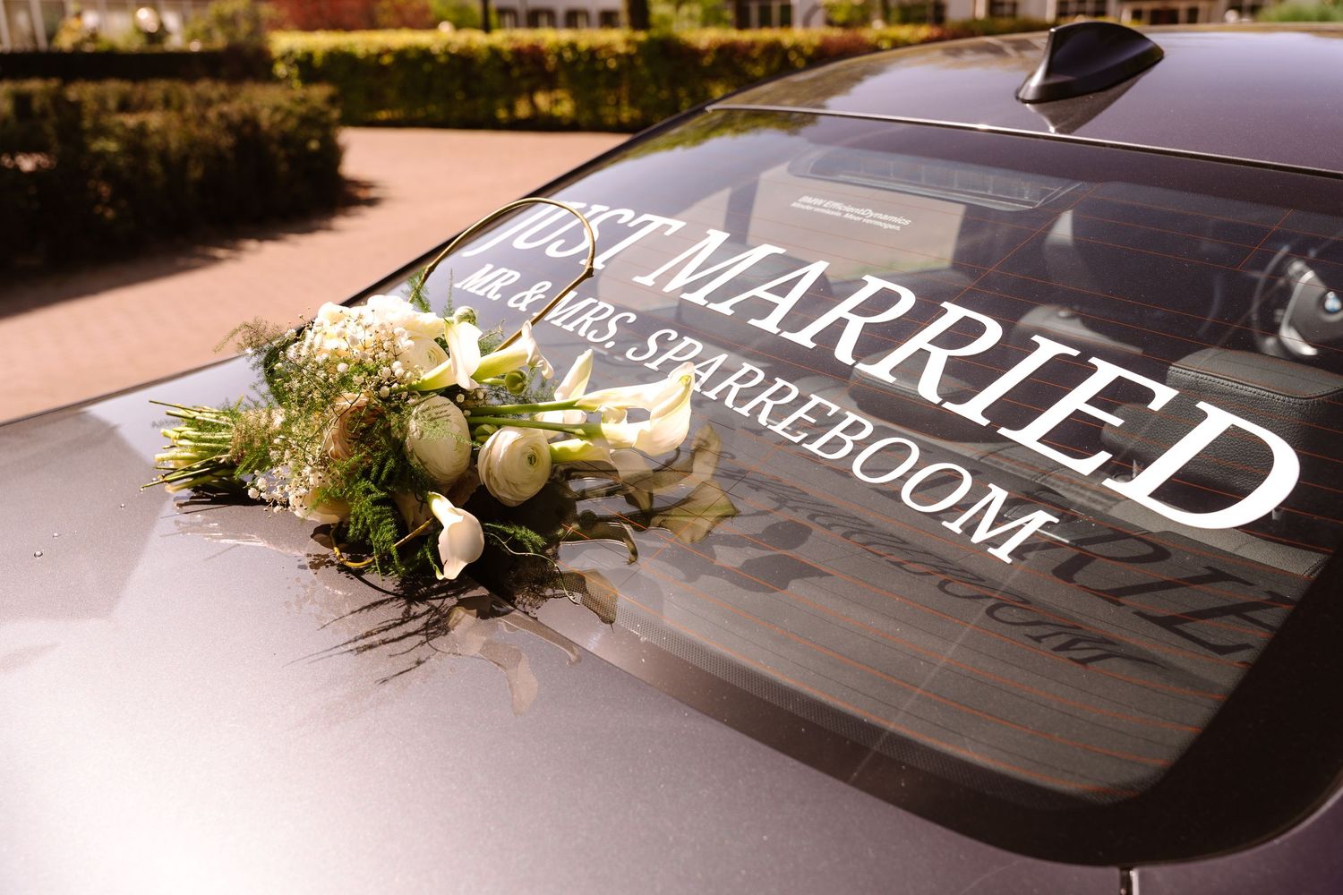 Just Married car decoration with white floral bouquet on hood, Mr. & Mrs. Sparreboom wedding sign on windshield.