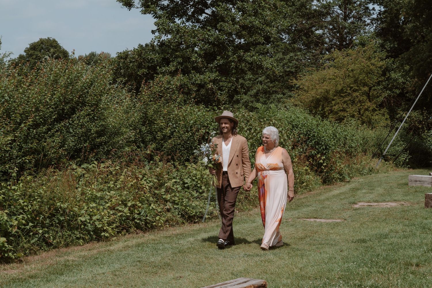 Wedding party walking through a lush green outdoor setting.