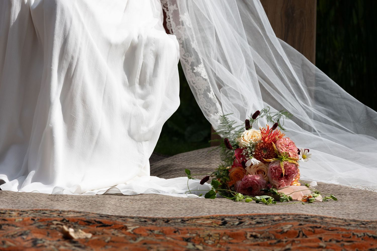 Wedding dress train flowing over floral arrangements on the ground.