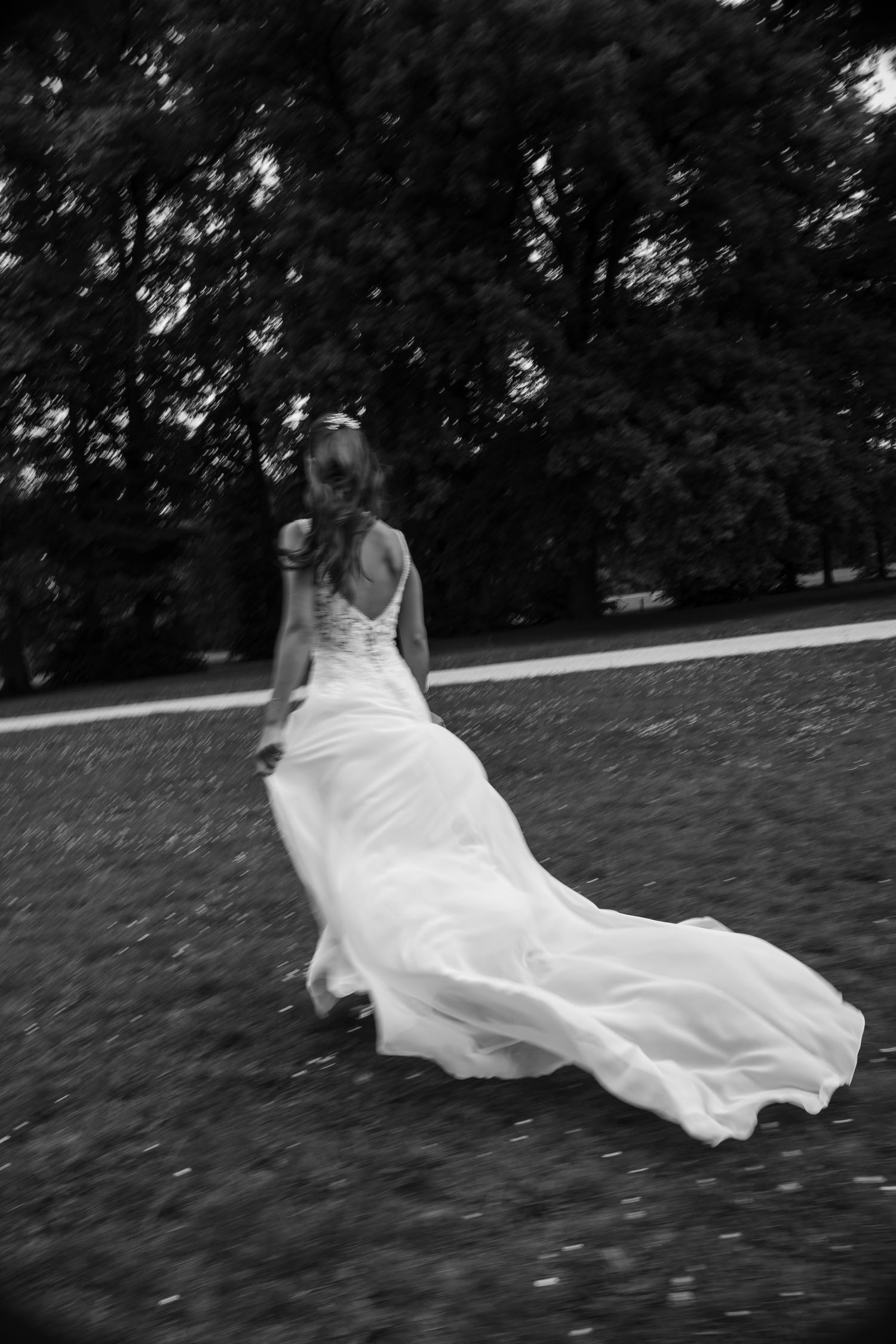 A flowing white wedding dress billows dramatically in black and white photography.