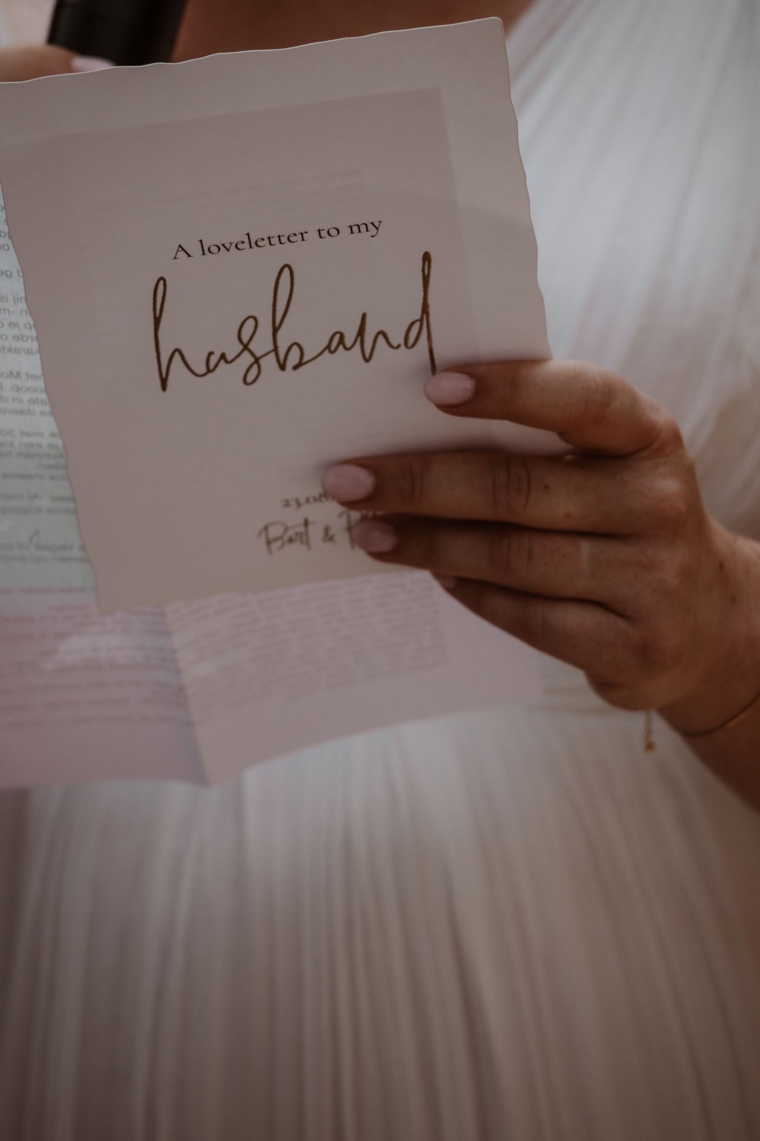 Close-up of hands holding a love letter during wedding preparations.