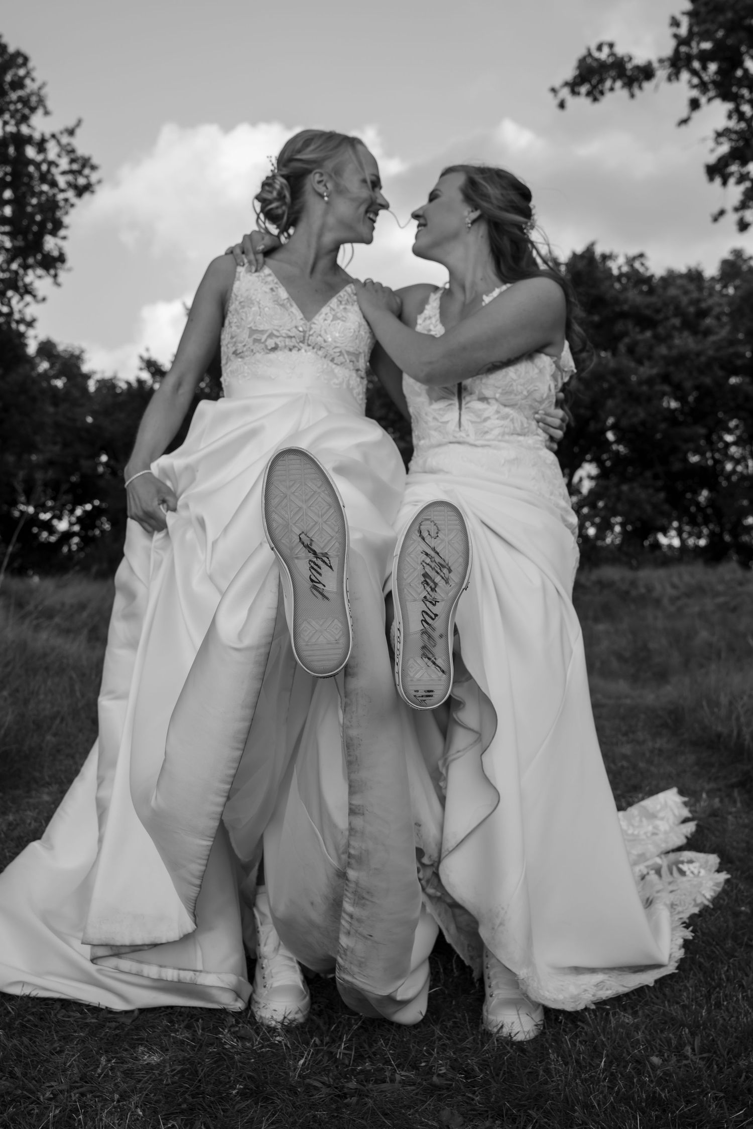 Black and white photo showing wedding couple's shoes while sitting together outdoors.