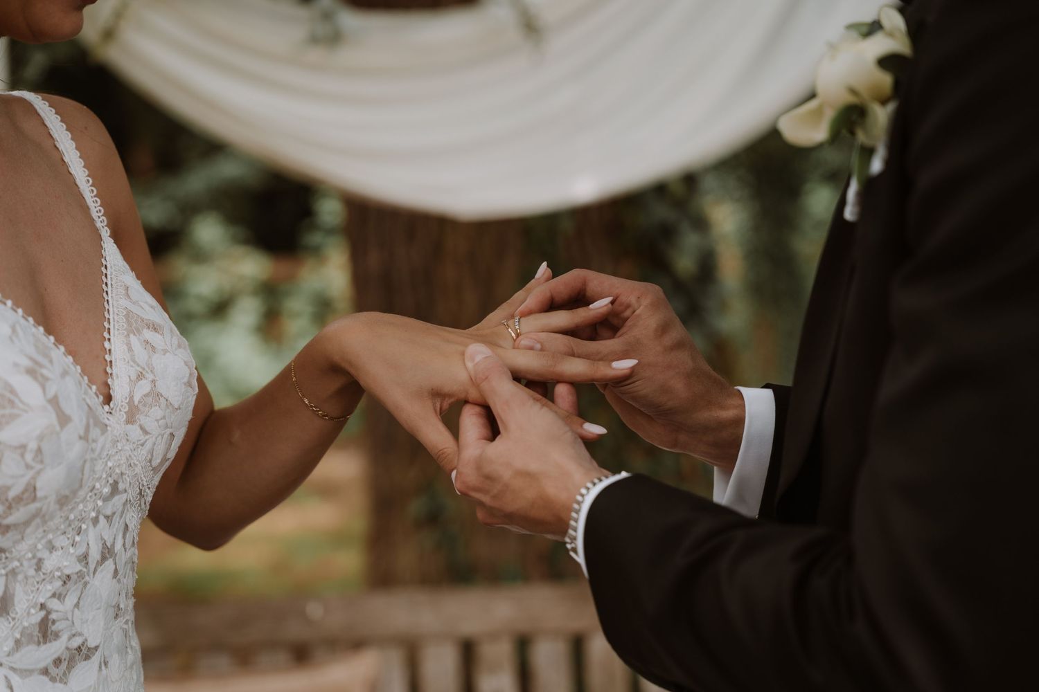 Close-up of wedding rings being exchanged during an outdoor ceremony.
