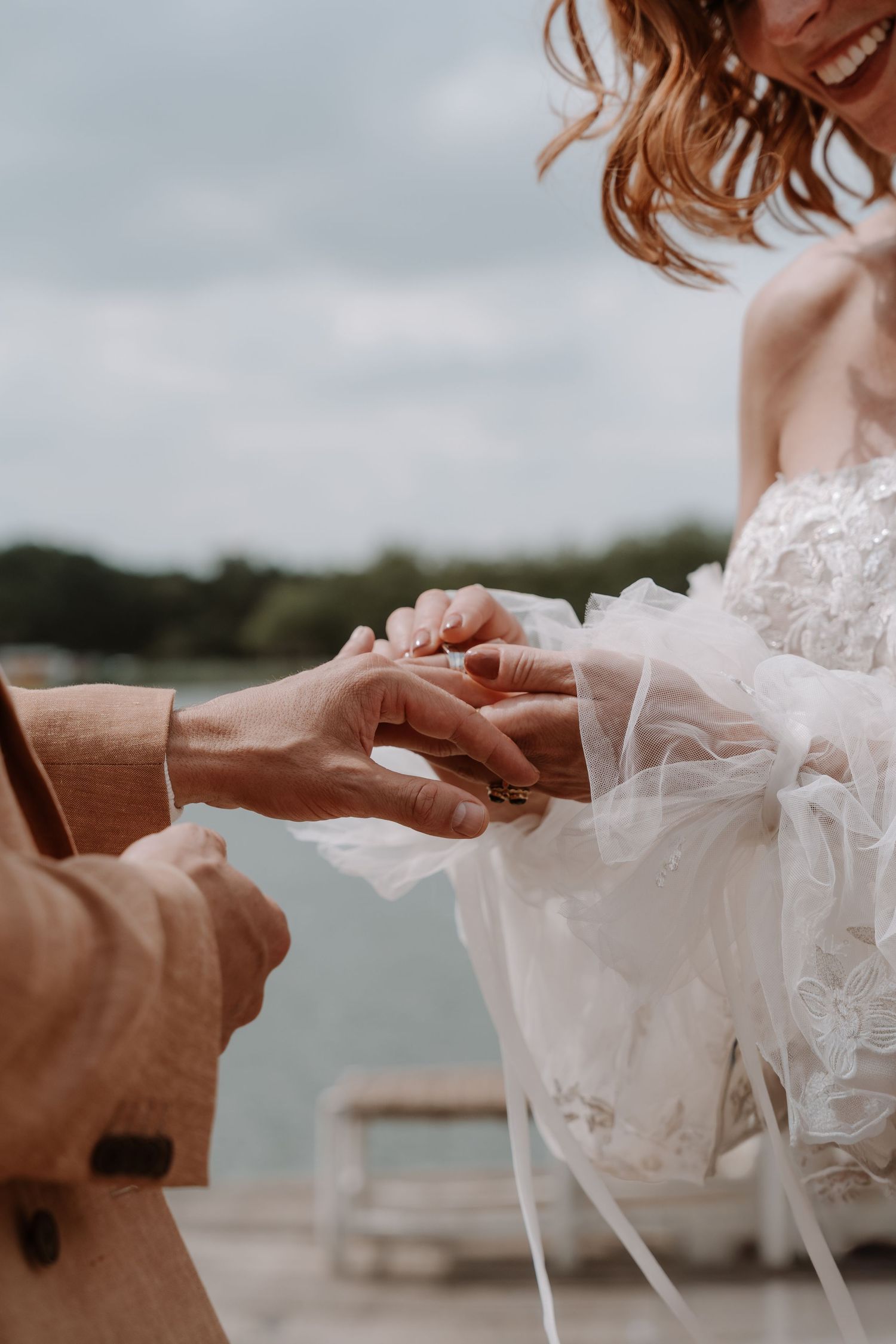 Close-up of wedding ring exchange during lakeside ceremony.