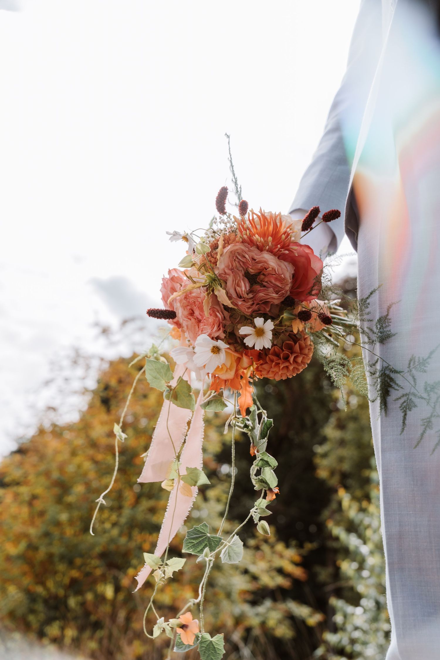 Coral and peach floral wedding decorations hanging against a bright sky.