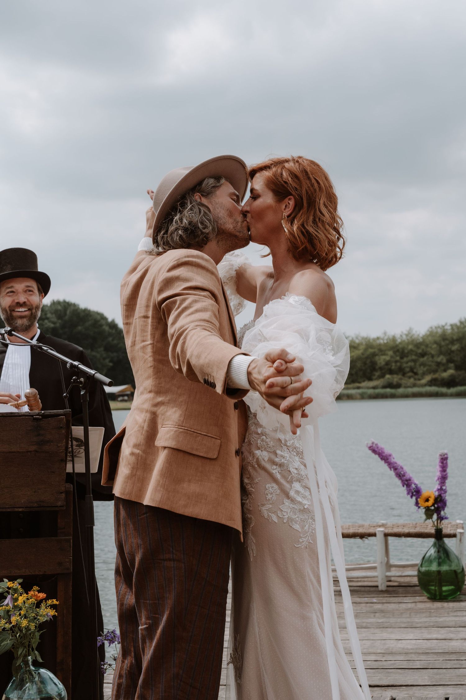 Lakeside wedding ceremony with tan and white attire against natural waterfront backdrop.