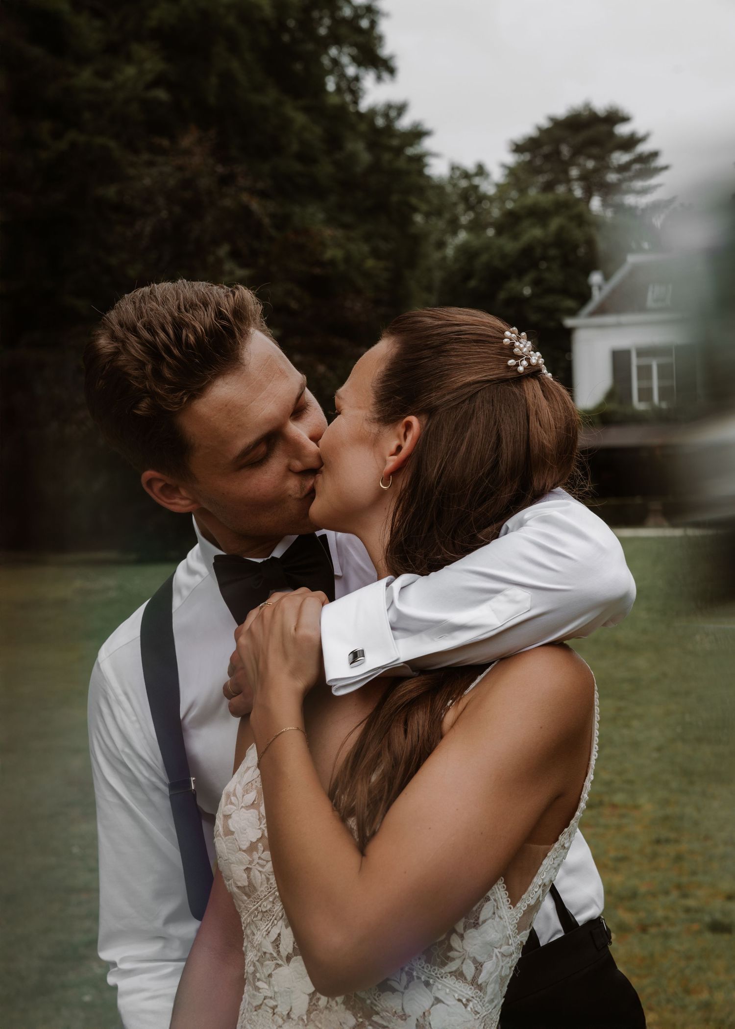 A tender wedding moment captured in front of a rustic countryside backdrop.