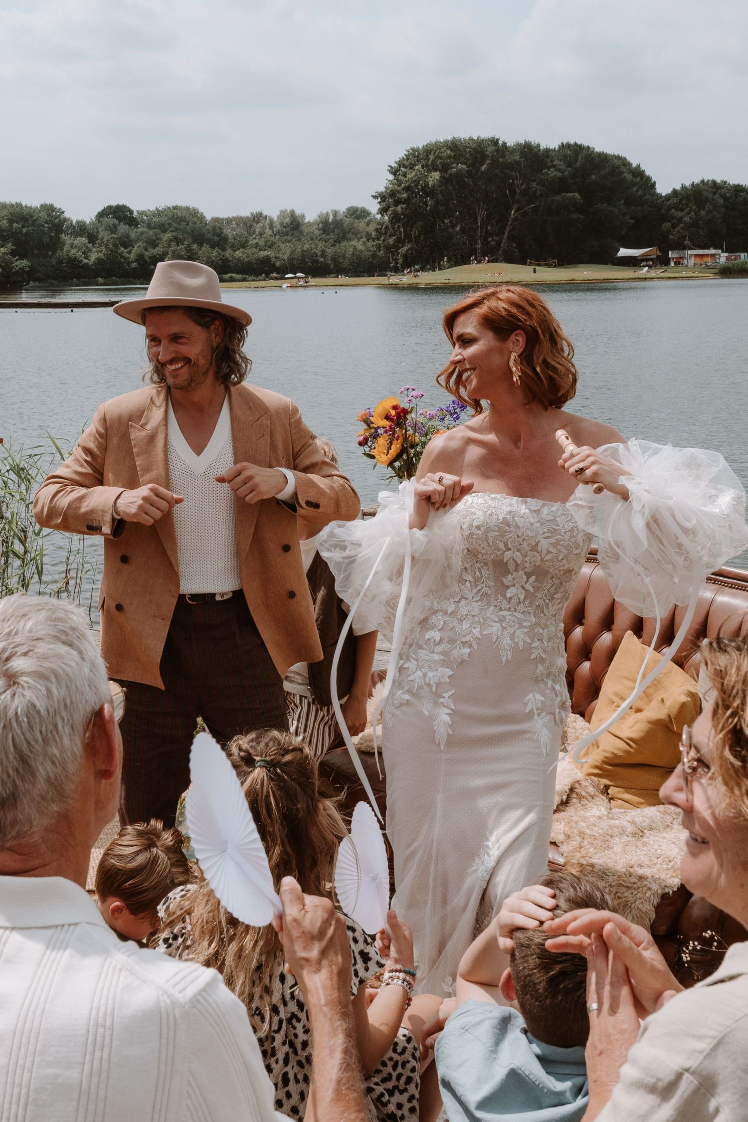 Wedding party celebrating on a dock with tan and white attire against a waterfront backdrop.