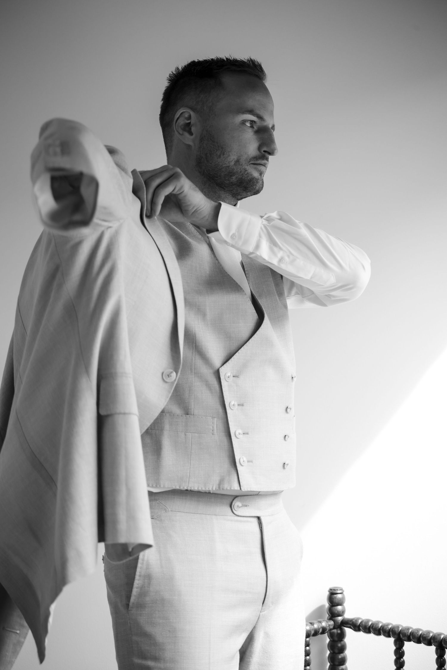 Groom getting dressed in a white suit before the wedding ceremony.