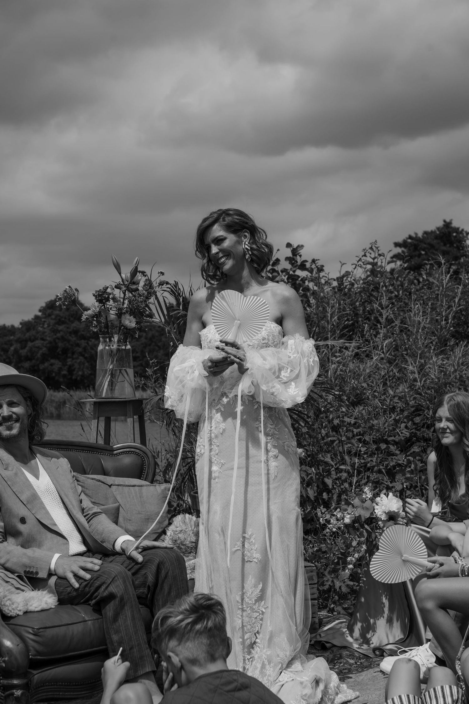 Black and white photograph of a wedding celebration with cloudy skies and natural scenery.