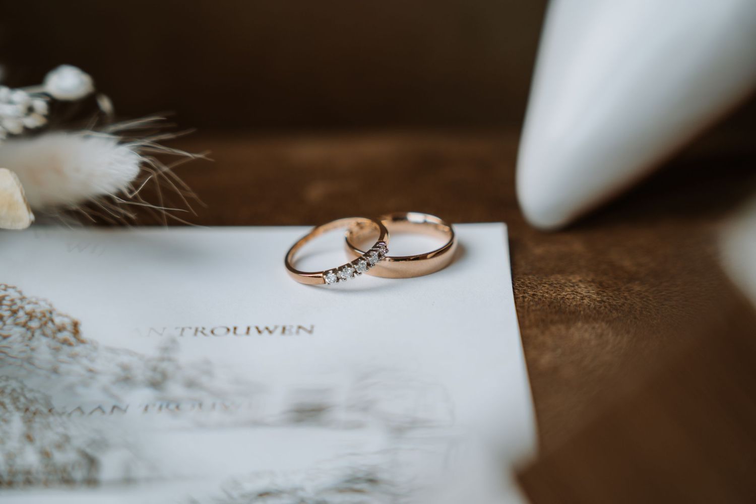 Wedding rings and invitation details photographed in soft focus.