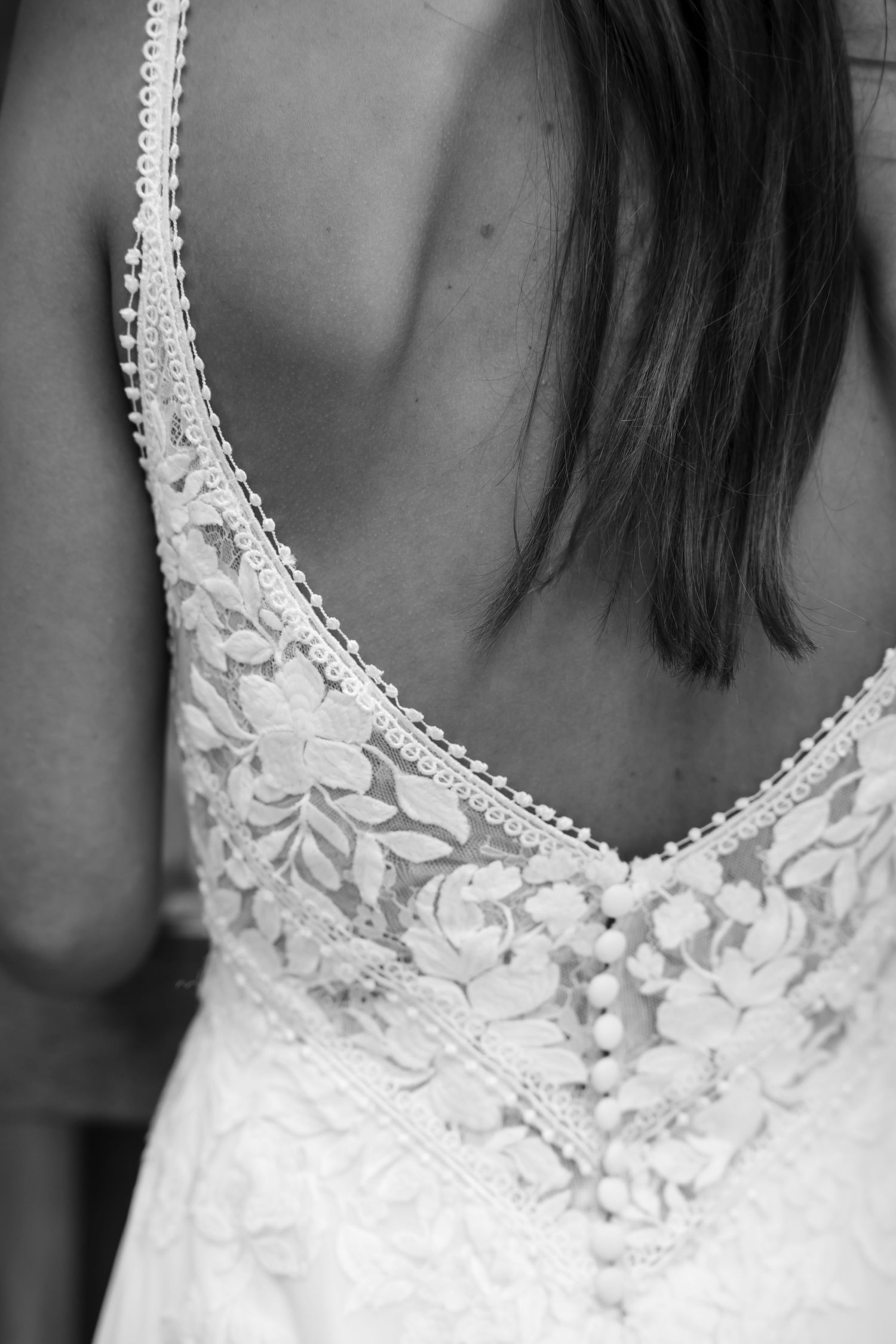 Detailed close-up of delicate lace and floral appliques on a white wedding dress neckline.
