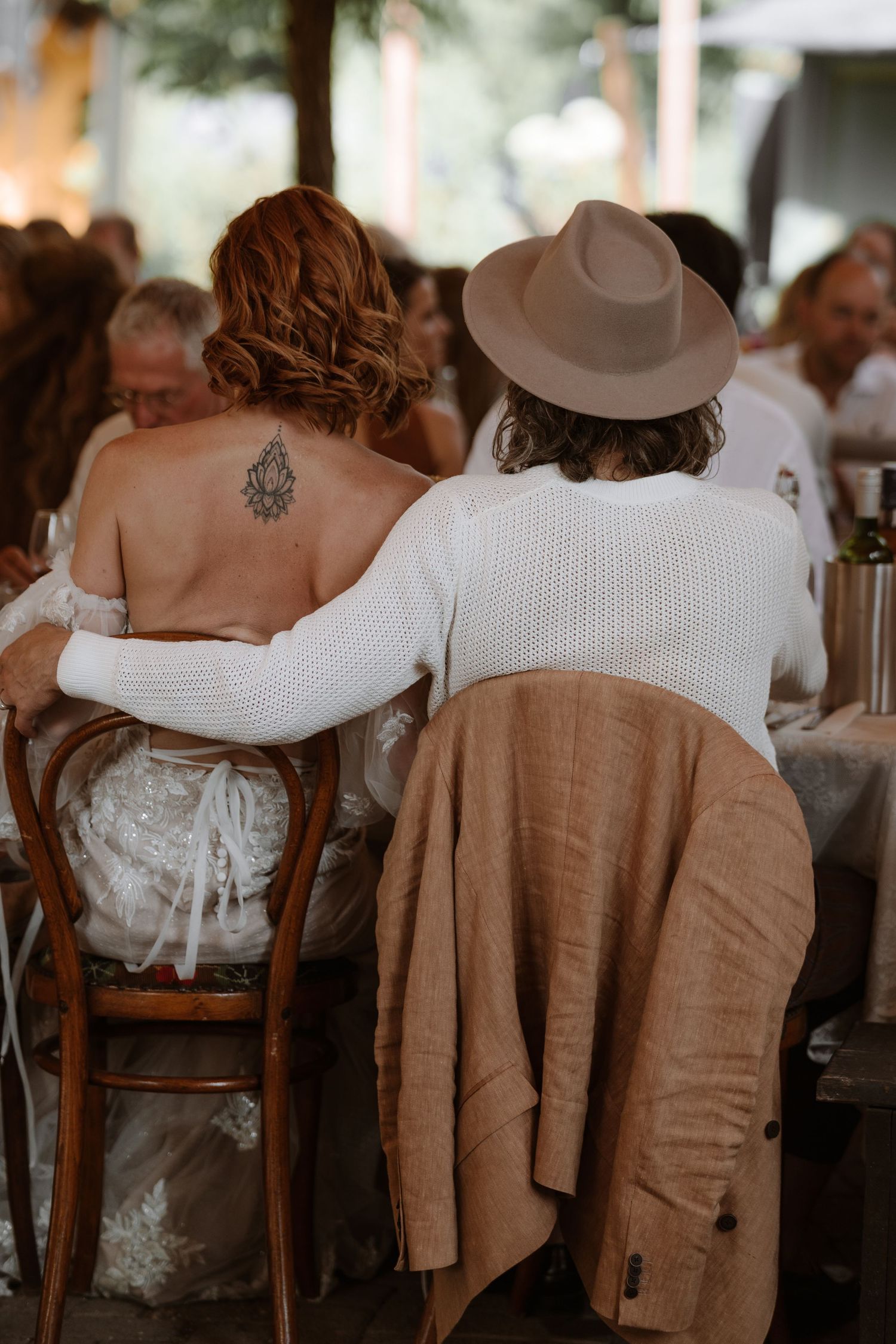 Row of people seated wearing neutral tones and white clothing at an outdoor event.